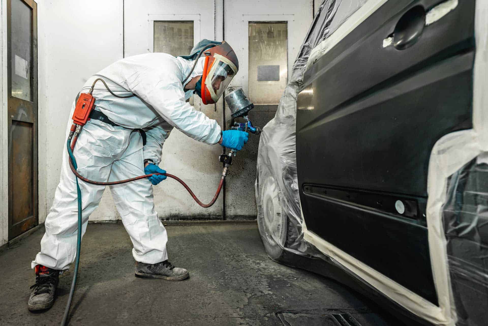 Spray painter refinishing a car in the Bushey Hall Garage bodyshop booth
